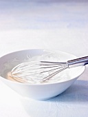 A bowl of yogurt with a whisk