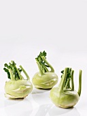 Three kohlrabi on a white surface