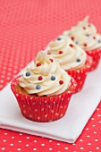 Three cupcakes decorated with red and blue sugar beads