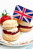 Two scones with strawberry jam, custard cream and a Union Jack