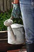 A woman carrying a watering can in the garden