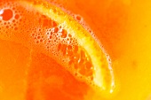 An orange slice in orange juice (close-up)