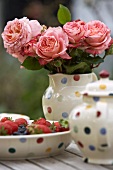 Bouquet of roses and strawberries on garden table