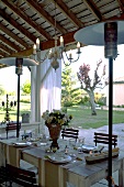 Festlich gedeckter Tisch auf überdachter Terrasse mit Gaspilzheizung und Blick in Garten