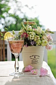 Refreshing drink and bouquet in metal bucket on table