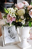 Festive bouquet in white china vase next to framed photo