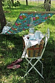 Crockery and picnic basket on chair in front of hammock hanging in garden
