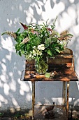 Selbstgepflückter Blumenstrauss auf rostigem Gartentisch vor der Hauswand