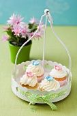 Four cupcakes decorated with pink and light-blue sugar flowers