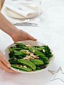 A woman serving a plate of vegetables with slivered almonds (Christmas)
