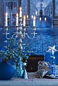 Lit candles in candlestick and Christmas decorations on table top