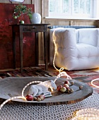 Plaster donkey, fairy lights, apples and nuts on wooden dish on rug