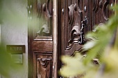 Holzgeschnitzte Eingangstür und moderne Türklingel in Hauswand
