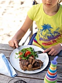 A girl eating a grilled steak with mushrooms