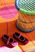 Bamboo stool and girl's shoes on colourful rug