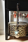 Jewellery hanging from wire above leopard-print storage box