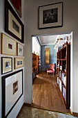 View from anteroom with gallery of pictures past bookcase in living room with parquet floor to pink Baroque chair