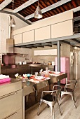 Designer Metallstuhl im Retrolook an Edelstahl Theke einer offenen Küche