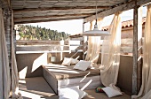 Summer atmosphere on veranda with comfortable daybed and airy curtains hanging from roof
