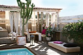 Summer atmosphere on terrace - pool and planters in front of terrace furniture below roof