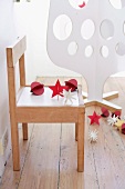 Christmas decorations on child's chair with white plywood Christmas tree in background