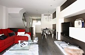 Red upholstered sofa, acrylic glass coffee table and wall-mounted shelves in designer apartment