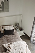 Bedroom in shades of grey with view down onto double bed with headboard and blanket