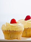 Two cupcakes with buttercream and raspberries