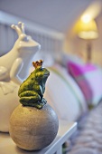 Froschfigur mit Krone sitzt auf einer Kugel