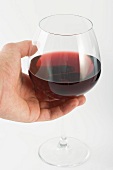 Hand hält ein Rotweinglas