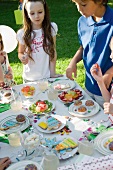 Children around sweets table at outdoor birthday party