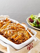 Gratinated penne pasta with bolognese sauce and cheese in a baking dish