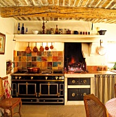 Mediterranean kitchen with brick ceiling and round beams above stylish retro cooker and open fireplace