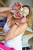 Young woman covering her eyes with cucumber slices