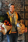 Mann trägt Einkaufstaschen mit Obst und Gemüse