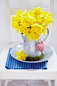 Bouquet of narcissus in zinc pitcher with moss wreath and small fabric heart