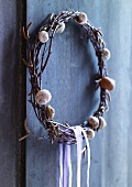 Wreath decorated with snail shells hanging on wooden wall