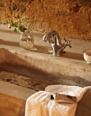 Concrete wash basin with vintage tap fittings against rustic wall