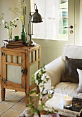 Upholstered couch and retro table lamp on small wooden cabinet in front of back door