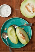 Honeydew Melon Cut into Wedges; Some Seeds Removed; Small Dish of Sea Salt