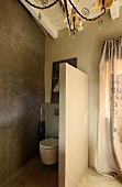 Toilet separated by partition with grey polished plaster wall to one side
