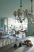 Vintage chandelier with glass ornaments above dining table in front of work station and lounge area in open-plan living room with traditional ambiance