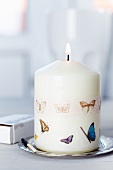 Lit candle decorated with butterfly-patterned tape