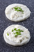 Sliced radish topped with cream cheese and chives
