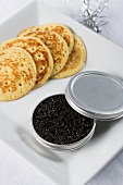 Black caviar in a tin with corn pancakes