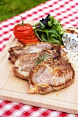 Grilled pork chops with sides on a chopping board