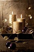Goldene Kerzen und lila Christbaumkugeln auf Tablett