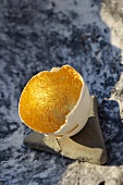 Aufgebrochene Eierschale mit vergoldeter Innenwand