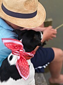 Angler sitzt mit Hund am Ufer