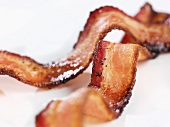 Two Pieces of Crispy Pepper Bacon on White Background; Close Up